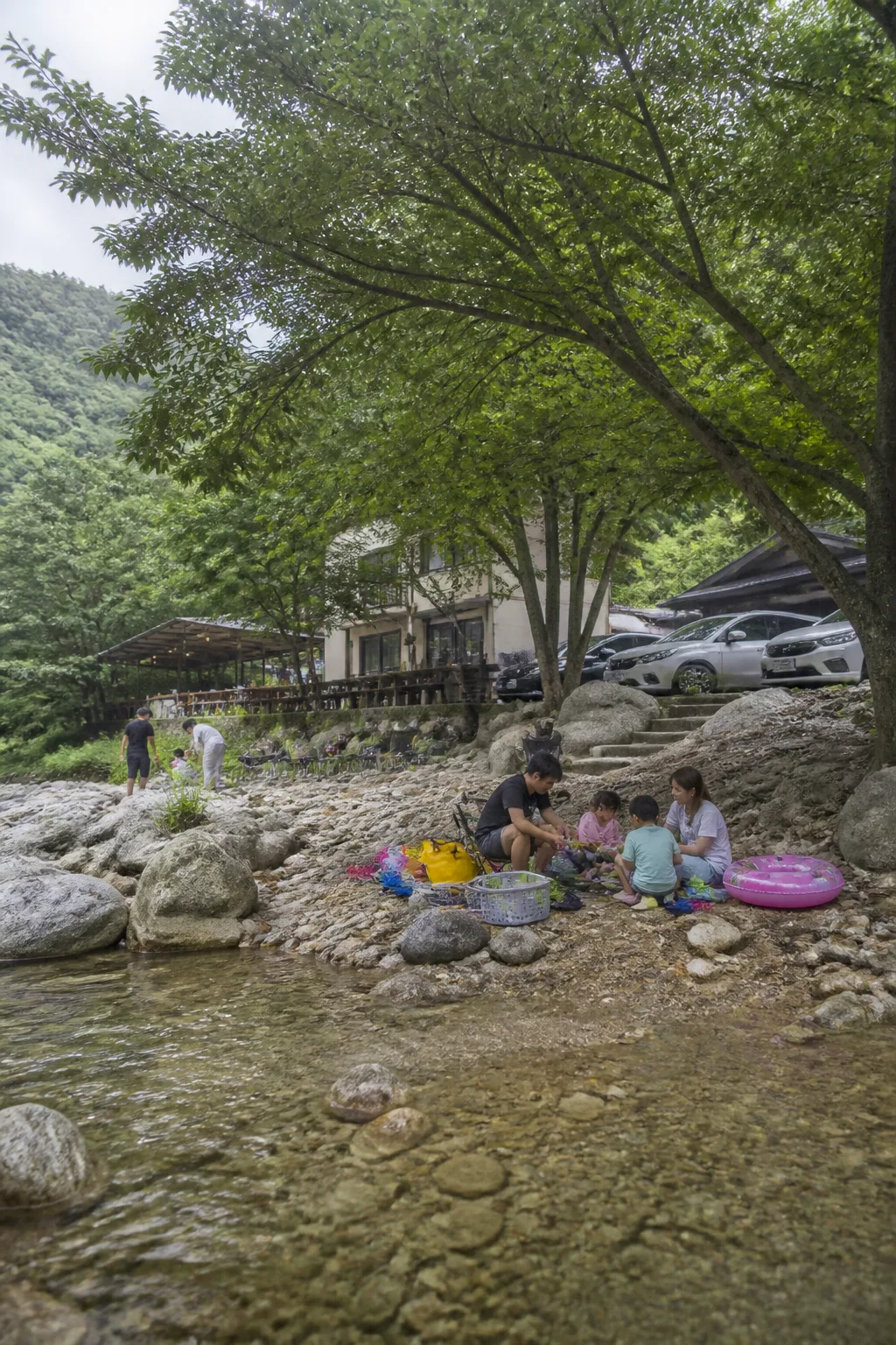계곡과 펜션, 주차 공간이 함께 보이는 강원도계곡펜션 여름 여행 장면